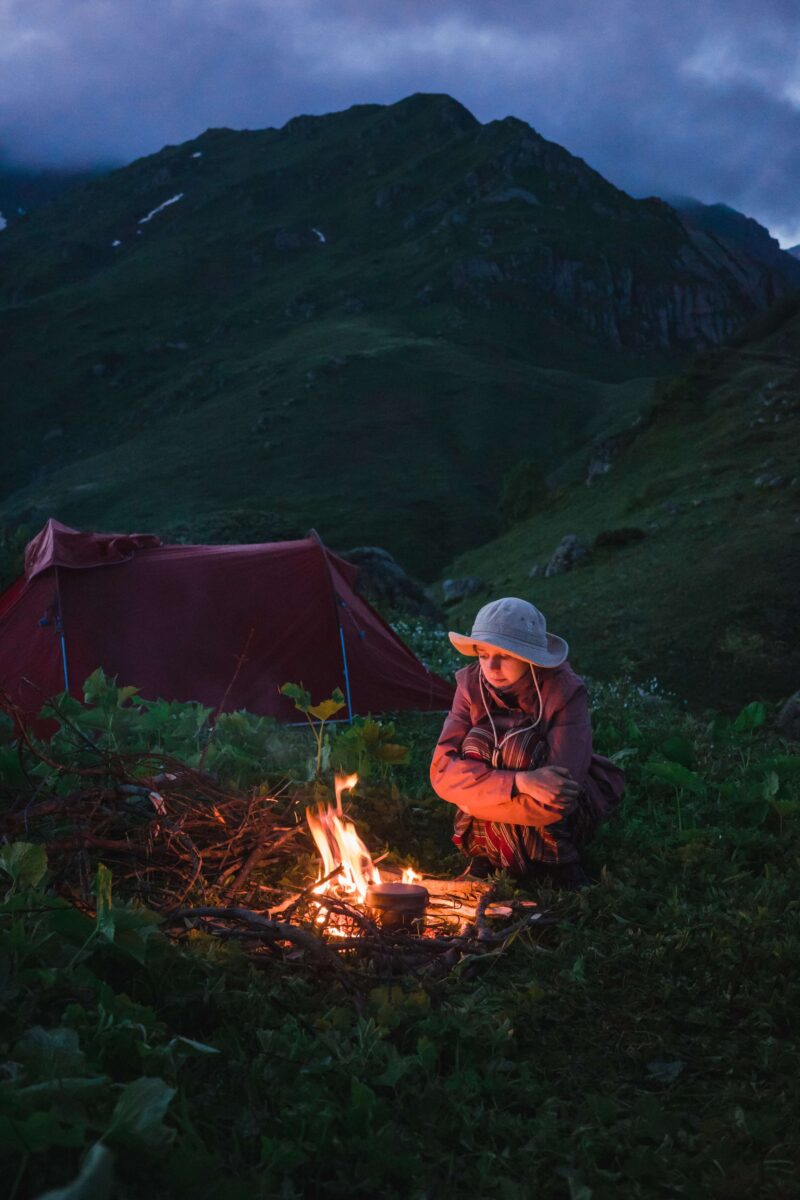 Anna Ivahnenko Sitting by a bonfire next to a tent