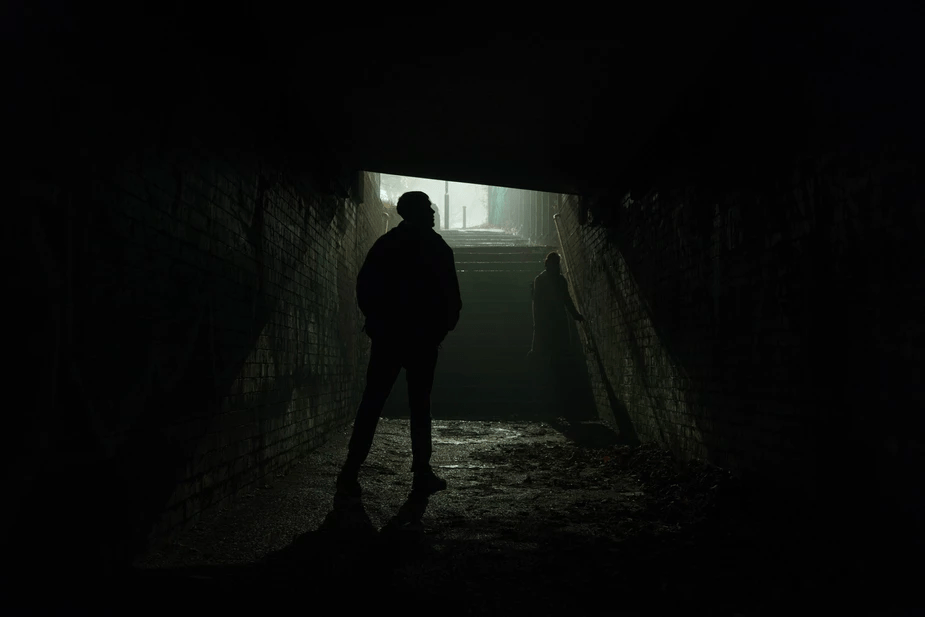 Two people standing in a tunnel on a foggy night