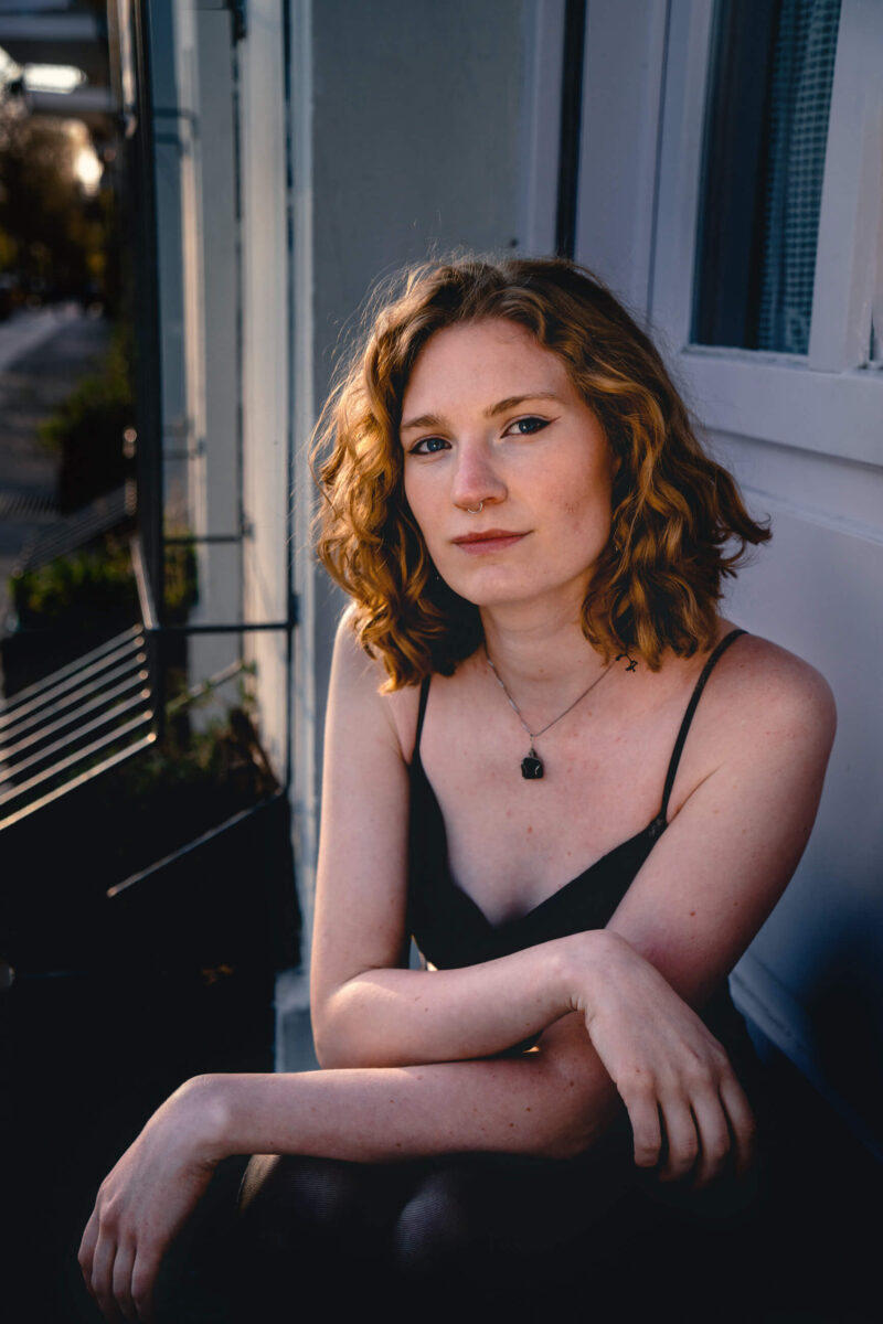 Portrait photography in Berlin: a young woman sitting on a bench on a street