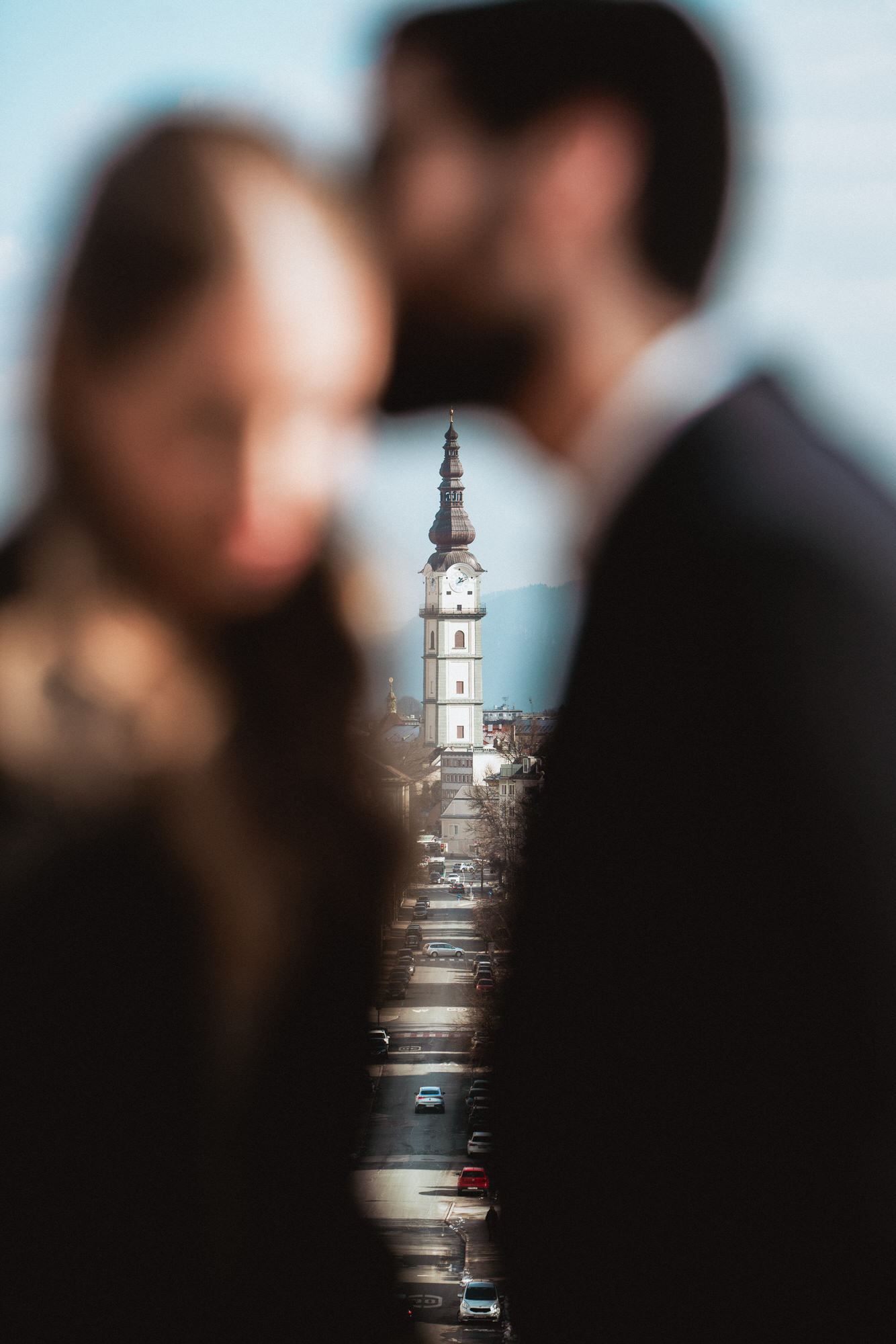 Fine art photo of groom kissing his bride with the view over an austrian city