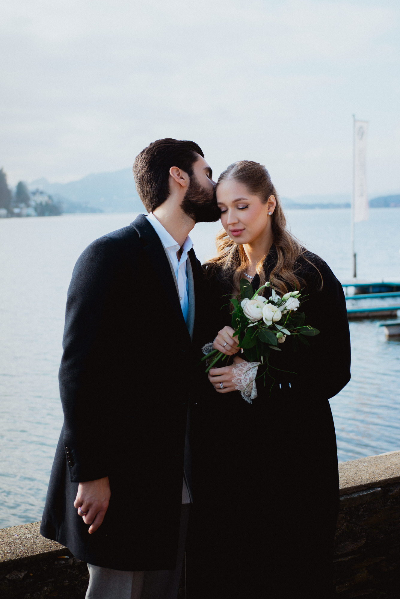 wedding photoshoot in austria: groom kisses his bride in front of Wörthersee