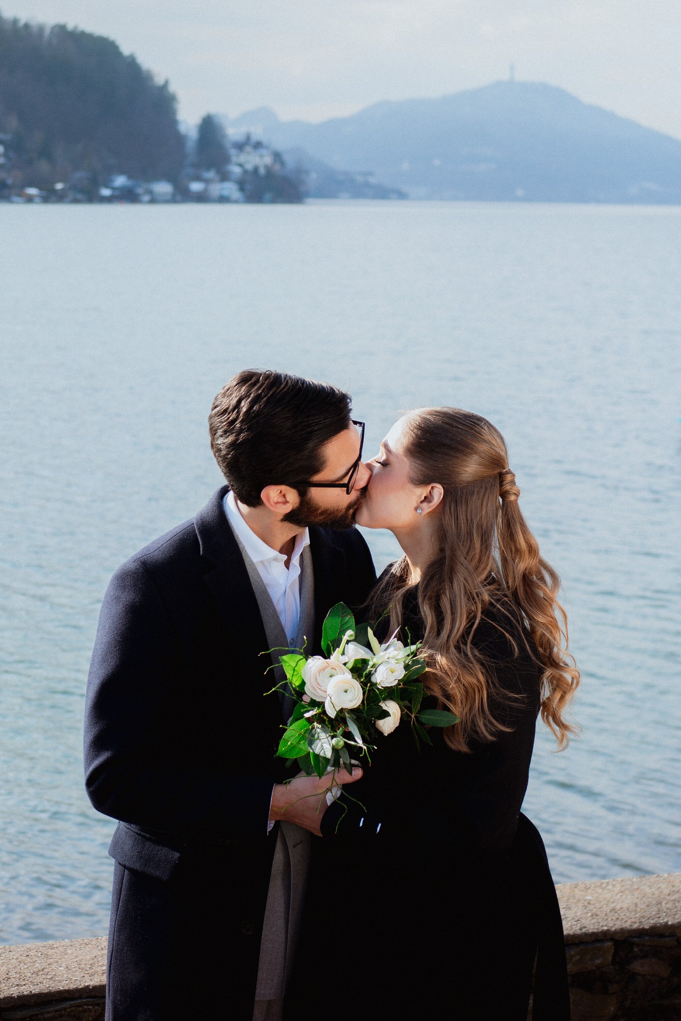 newlyweds kissing in a stunning location in austria in front of a lake